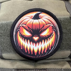 May include: A black and orange Halloween patch with a scary jack-o'-lantern face. The pumpkin has a wide, toothy grin and glowing eyes.