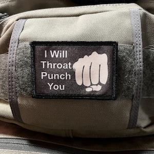 Puede incluir: Un parche negro con texto blanco que dice "I Will Throat Punch You" y un gráfico de puño blanco.