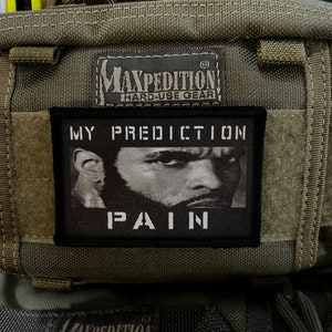 Op de afbeelding: Een groene Maxpedition tas voor zwaar gebruik met een zwart patch waarop "My Prediction Pain" staat.