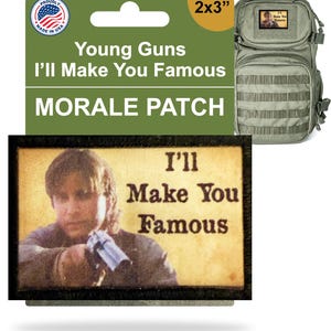 Puede incluir: Un parche moral rectangular con el texto "I'll Make You Famous" y una imagen de una persona sosteniendo un arma. El parche mide 5 x 7.6 cm y se muestra con una mochila verde.