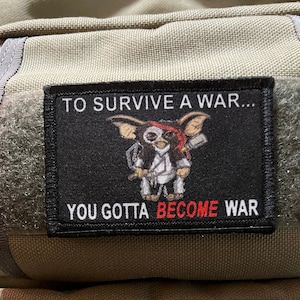 May include: Black and white patch featuring a cartoon character holding a weapon. The text on the patch reads "To survive a war... You gotta become war."