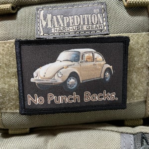 May include: A black patch with a white Volkswagen Beetle and the text "No Punch Backs." The patch is attached to a green Maxpedition bag.