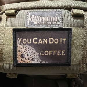 Puede incluir: Una mochila verde Maxpedition con un parche negro que dice "You Can Do It - Coffee".