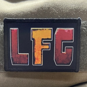 Puede incluir: Parche negro con las letras LFC en un degradado rojo, naranja y amarillo. Las letras están delineadas en negro.