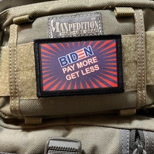 May include: A black and red patch with the text "BIDEN PAY MORE GET LESS" on a green tactical backpack.