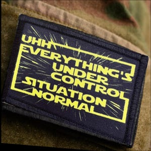 May include: A rectangular black fabric patch featuring a yellow border and yellow text which reads UHH EVERYTHING'S UNDER CONTROL SITUATION NORMAL. The lettering is set against a star-like burst effect, providing a clear and high-contrast visual design.