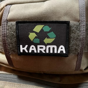 May include: A black patch with a green and yellow recycling symbol and the word "KARMA" in white text.