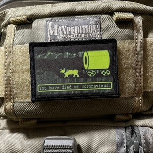 Könnte beinhalten: Ein schwarzer Patch mit einem grünen, pixeligen Bild eines Panzers und dem Text "you have died of coronavirus." Der Patch ist an einer grünen Maxpedition Hard-Use Gear Tasche befestigt.