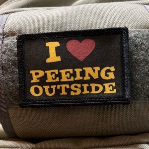 May include: A black patch with a white heart and yellow text that reads "I ♥ PEEING OUTSIDE".