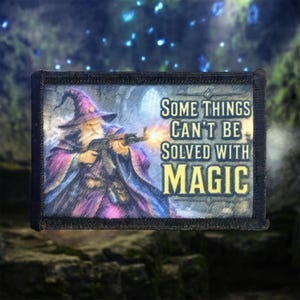 Könnte beinhalten: Ein rechteckiger Aufnäher mit einem Zauberer in einer violetten Robe, der ein Gewehr hält, mit einem Mündungsfeuer und dem Text "SOME THINGS CAN'T BE SOLVED WITH MAGIC" in gelben Großbuchstaben auf dunklem, strukturiertem Hintergrund.