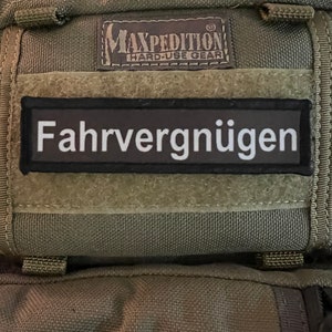 May include: A green Maxpedition Hard-Use Gear bag with a black patch that says "Fahrvergnügen" in white letters.