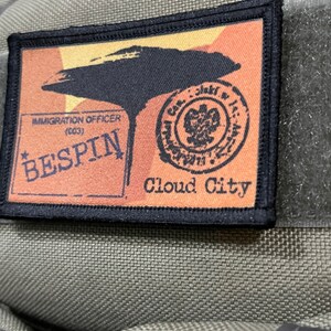 May include: A black and orange embroidered patch with the text "Bespin Cloud City" and a stamp that says "Immigration Officer (003)".