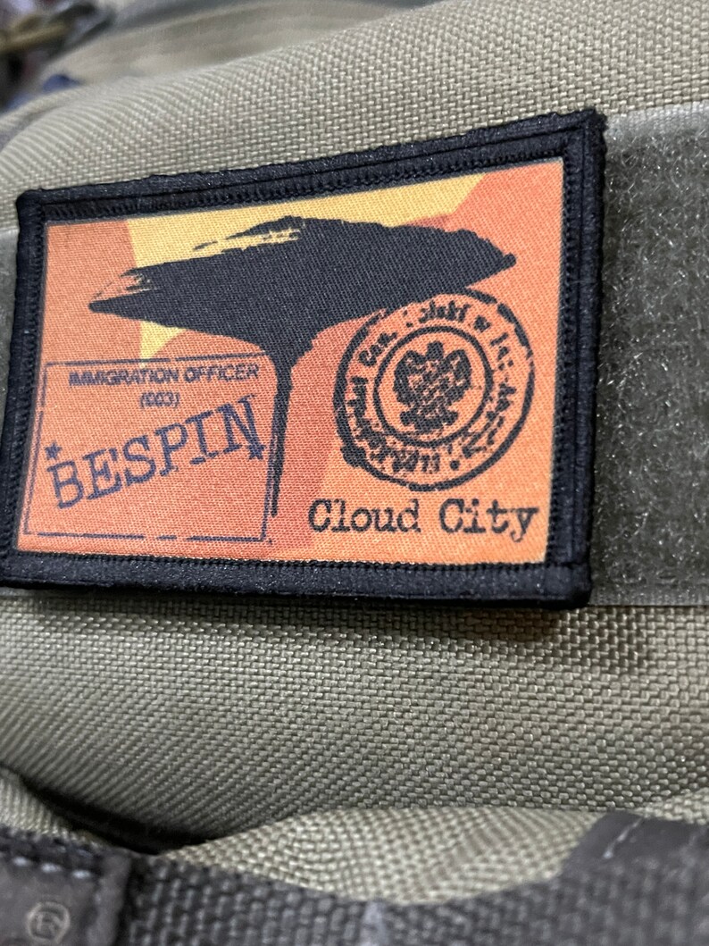May include: A black and orange embroidered patch with the text "Bespin Cloud City" and a stamp that says "Immigration Officer (003)".