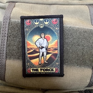 Op de afbeelding: Een zwart-witte patch met een Star Wars-thema. De patch toont een personage uit de film Star Wars: Een nieuwe hoop. Het personage staat in een woestijnlandschap. De tekst "THE FORCE" is op de patch gedrukt.