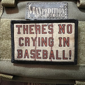 Può includere: Una toppa nera e arancione con il testo "THERE'S NO CRYING IN BASEBALL!" su uno sfondo verde. La toppa è attaccata a una borsa verde con il testo "MAXPEDITION HARD-USE GEAR" su di essa.