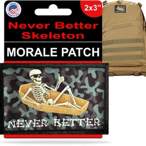 Puede incluir: Un parche moral de 5 x 7,6 cm con un esqueleto en un ataúd y las palabras "Never Better". El parche tiene un borde negro y un fondo de camuflaje. Una mochila de color canela está en el fondo.