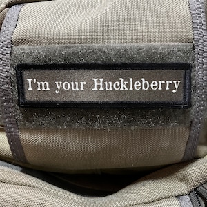 May include: A gray fabric bag with a black patch that says "I'm your Huckleberry".