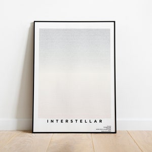 May include: A black framed poster with a gradient background of light blue, white, and pink. The poster has the word "INTERSTELLAR" printed in black at the bottom.
