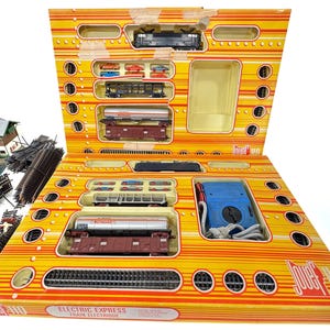 May include: A vintage Jouef Electric Express train set in its original box. The box is yellow and orange with a train layout design. The set includes various train cars, tracks, and a blue control box. The text "Electric Express Train Electrique" is visible.