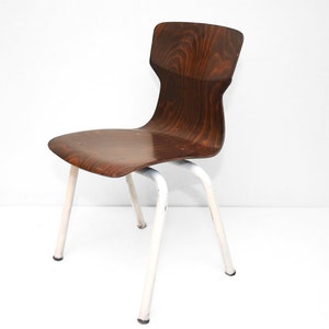 Puede incluir: Una silla de madera marrón con un marco de metal blanco. La silla tiene un respaldo curvo y un diseño simple.