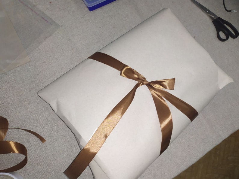 May include: A white gift bag with a brown satin ribbon tied in a bow.