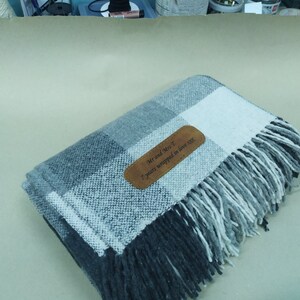 May include: A gray and white plaid throw blanket with a brown leather tag that says "Mr and Mrs T 7 years wrapped in love xxx".