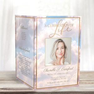 May include: A folded funeral program with a sky background and a photo of a woman. The program includes the text "A Celebration of Life" and the name "Chamille S. Crawford". The program also includes the dates "May 12th, 1975 - January 22nd, 20XX" and the text "Church of the Holy Cross, 123 N 28th Street, New York, NY 10001, Sunday, January 28th, 20XX, 10:00 AM."