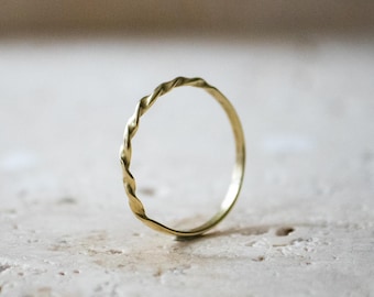 May include: A simple gold ring with a twisted band design.