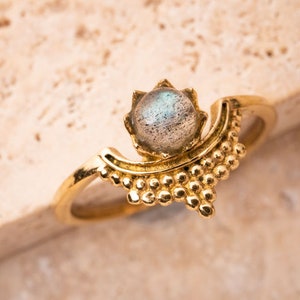 Puede incluir: Un anillo de oro con un diseño de media luna y una piedra preciosa redonda e iridiscente en el centro.