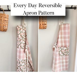 May include: Two reversible aprons hanging on a wall. One apron features a pink plaid pattern, while the other has a floral design. The aprons are hanging on hooks, with a woven basket on the left. Text above reads "Every Day Reversible Apron Pattern."