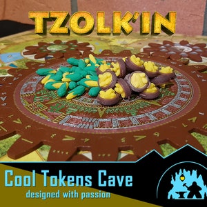 Puede incluir: Primer plano de un tablero de juego con una pieza marrón en forma de engranaje en el centro. El engranaje está rodeado de un diseño colorido y tiene una pila de fichas de maíz amarillo y verde y una pila de fichas moradas y amarillas en la parte superior. El texto "TZOLK'IN" es visible en la parte superior central de la imagen. El texto "Cool Tokens Cave designed with passion" es visible en la parte inferior de la imagen.