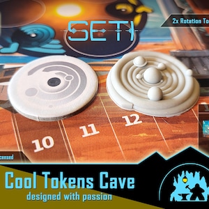 May include: Two gray game tokens with a planetary design and a spiral design, respectively, on a game board. The tokens are labeled "SET" and "Cool Tokens Cave". The game board has the numbers 10, 11, and 12.