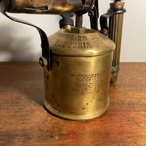 Pode incluir: Um ma&ccedil;arico vintage de lat&atilde;o com uma pega preta e um r&oacute;tulo que diz "12H JAPOURIA THE ORIGINAL & BENLINE IS ALWAYS STANDARD MAX SIEVERT"