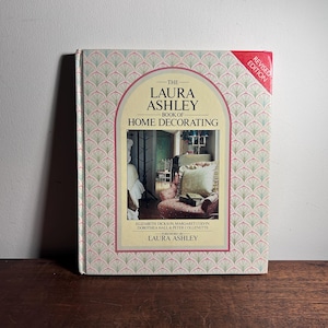 Puede incluir: Un libro de tapa dura titulado "The Laura Ashley Book of Home Decorating". La portada presenta un patrón de abanico rosa y verde con una imagen central de una habitación decorada. Es una edición revisada.