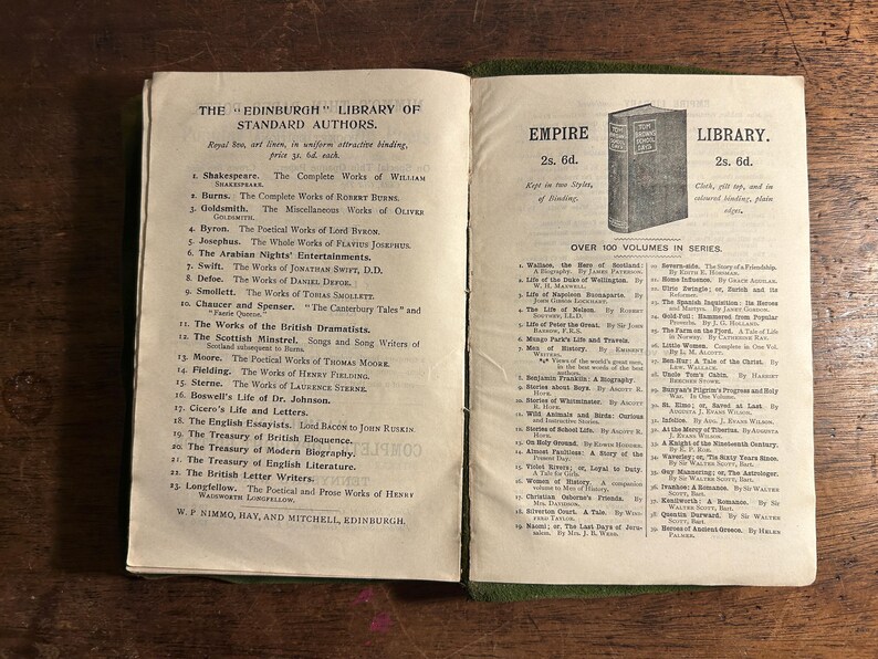 Pode incluir: Livro aberto com texto de "The Edinburgh Library of Standard Authors" e "Empire Library". As p&aacute;ginas est&atilde;o envelhecidas, com uma lombada verde. O texto lista autores e t&iacute;tulos de livros.
