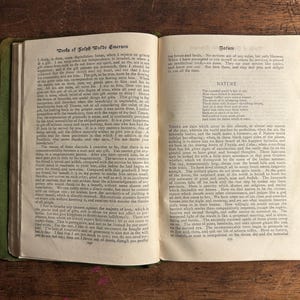 Pode incluir: Livro aberto com capa verde, exibindo texto de "Works of Ralph Waldo Emerson" e "Nature". As p&aacute;ginas est&atilde;o envelhecidas, com texto vis&iacute;vel. O livro est&aacute; aberto sobre uma superf&iacute;cie de madeira.