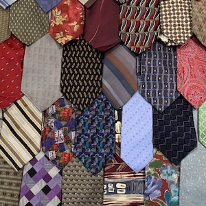 Puede incluir: Una colcha de retazos hecha de una variedad de corbatas estampadas. La colcha está hecha de formas hexagonales, cada una de las cuales es una corbata diferente. Las corbatas son de varios colores, incluyendo azul, rojo, verde y marrón.