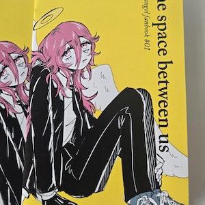 Könnte beinhalten: Mehrere gelbe Fanbücher mit dem Titel "the space between us" und "akiangel fanbook #01". Das Cover zeigt eine Manga-artige Illustration einer Person mit rosa Haaren, einem schwarzen Anzug und blauen Turnschuhen.