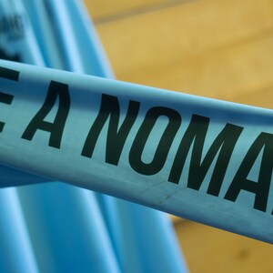 May include: A light blue long-sleeved shirt with the text "BE A NOMAD" printed in black.