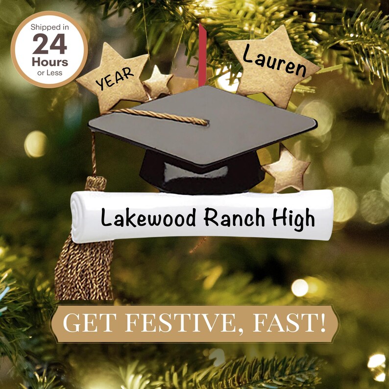 May include: A graduation cap ornament with a diploma scroll, a gold tassel, and stars. The scroll reads "Lakewood Ranch High". The ornament is decorated with the text "YEAR" and "Lauren".