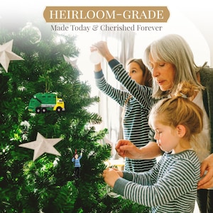 May include: Three people, two children and an adult, decorate a Christmas tree with ornaments. The tree is decorated with a green and yellow garbage truck ornament, a white star ornament, and a small figurine ornament. The text on the ornament reads "Year Travis".
