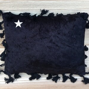 May include: Black velvet pillow with a white star in the center and black tassels around the edges.