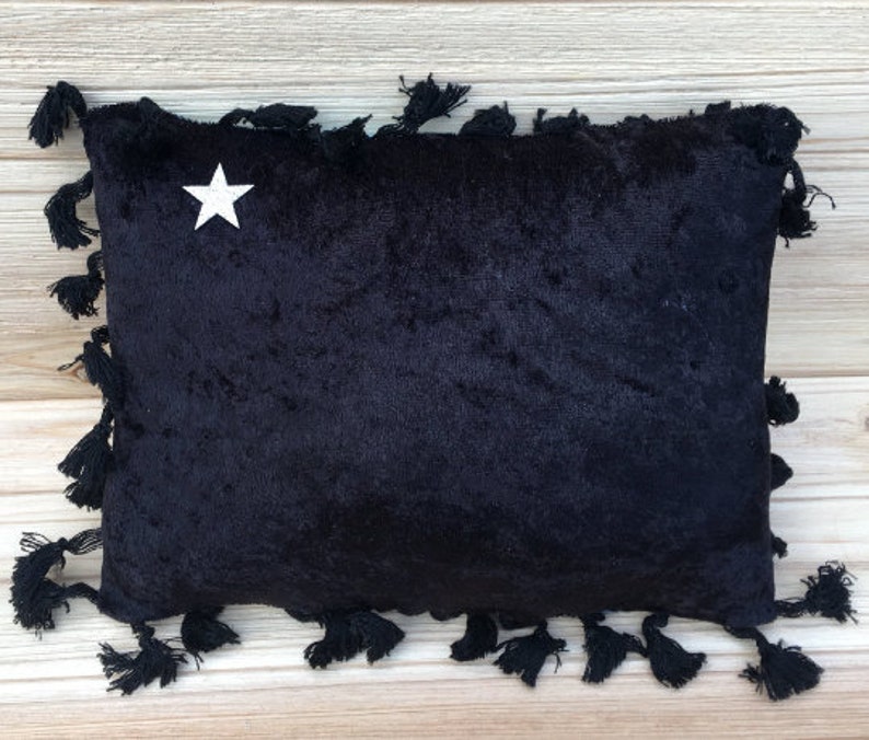 May include: Black velvet pillow with a white star in the center and black tassels around the edges.