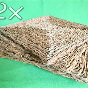 May include: Two woven square mats made of natural straw, stacked on top of each other. The mats are light brown in color and have a rough texture.
