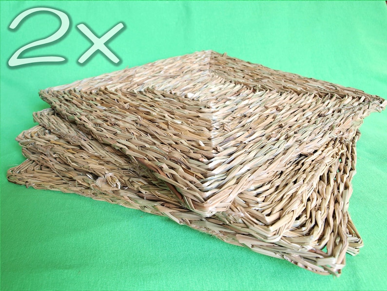 May include: Two woven square mats made of natural straw, stacked on top of each other. The mats are light brown in color and have a rough texture.
