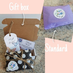 May include: A gift box with a tag that says "A gift for you!" and a butterfly graphic. The box contains a small package wrapped in black paper with white polka dots and tied with twine. A sticker with a floral design and the words "Just for you!" is on the package.