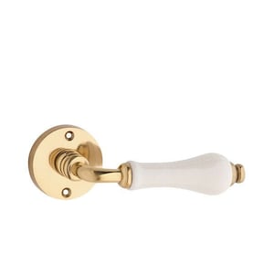 May include: A gold door handle with a white ceramic lever. The handle has a round base with two screws.