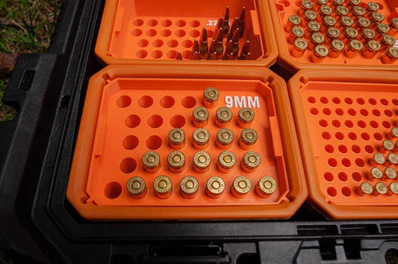 May include: A black storage case with orange compartments filled with ammunition. One compartment is labelled "9MM". Various bullets are visible, including .22 calibre and 9mm rounds, neatly arranged in rows.