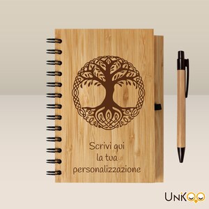 Könnte beinhalten: Ein braunes Bambus-Notizbuch mit Spiralbindung und einem Stift. Das Notizbuch hat ein Lebensbaum-Design und den Text "Scrivi qui la tua personalizzazione".