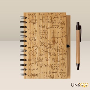 Può includere: Un taccuino in legno con rilegatura a spirale presenta una varietà di equazioni e formule matematiche stampate sulla copertina. Il taccuino è accompagnato da una penna in legno con una cartuccia d'inchiostro nero.